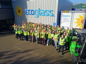Group of employees in high-visibility vests outside an industrial building labeled "Ecoglass," showcasing corporate photography.